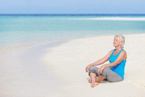 woman over 50 meditating on a beach