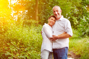 Happy smiling senior couple standing in a forest in summer