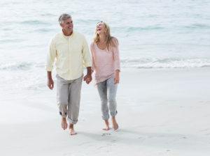 Happy couple walking by the sea at the beach